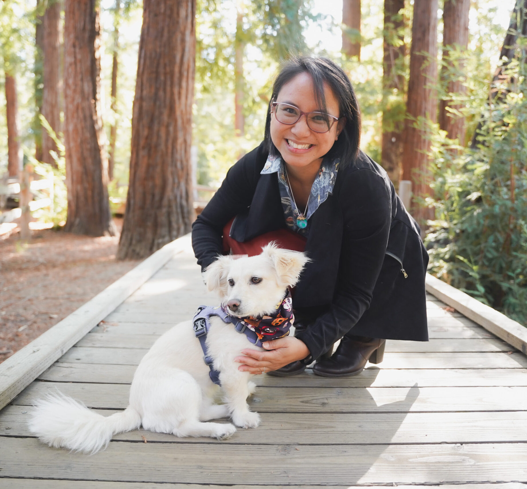 Jean poses with her dog, Chloe; redwoods can be seen in the background