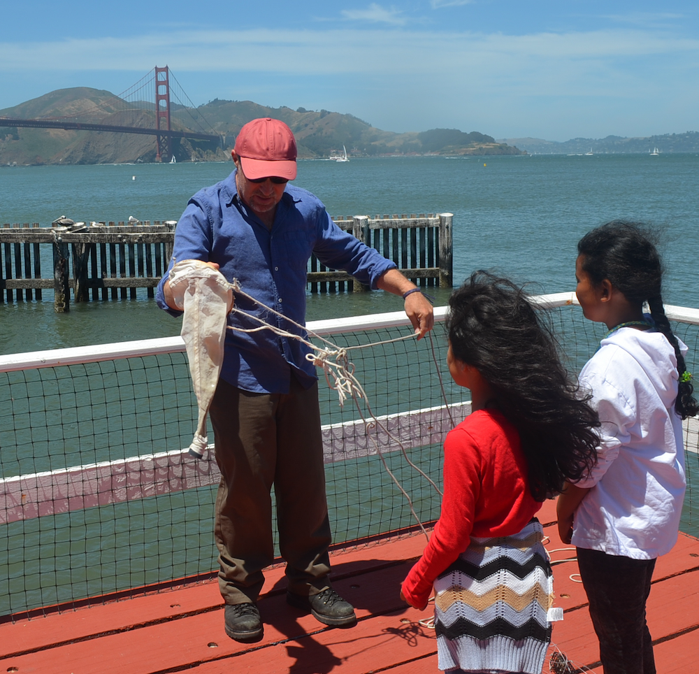 Plankton Discovery Family Workshop in action. Greater Farallones and Cordell Bank Marine Science Educator Peter Winch gives demonstration to two attendees of a plankton tow off the Greater Farallones pier on San Francisco Bay. Photo Credit: Justin Holl, NOAA