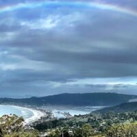 Aerial image of Bolinas Lagoon in the distance and the ocean on the left. A large rainbow above. Credit: Clint Graves