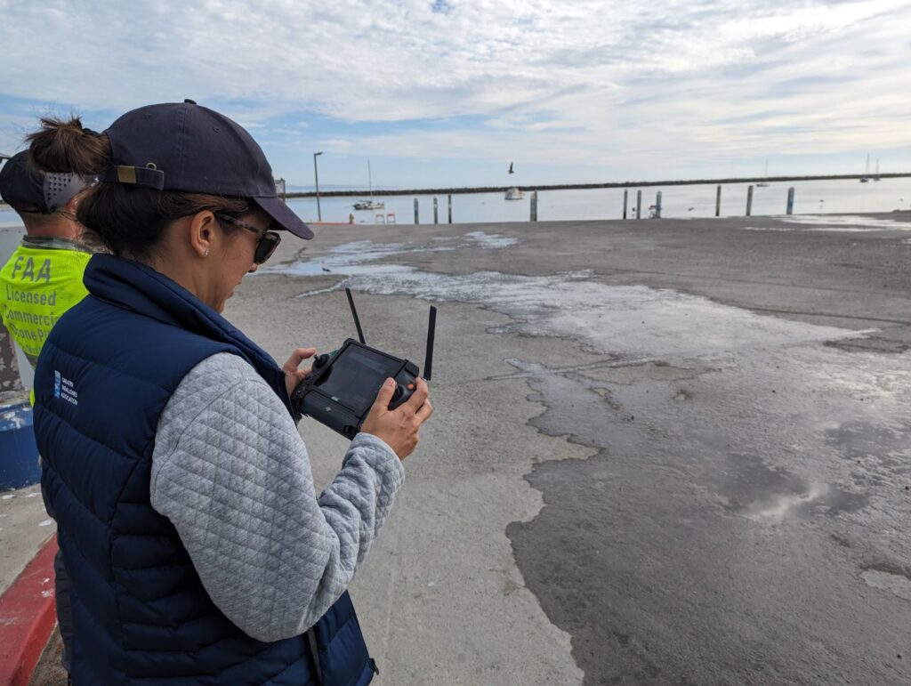 Dr. Wendy Kordesch operates a drone along the California coastline on a cloudy day.